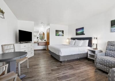 Wide view of a King Room with the king bed, armchair, television and dining table