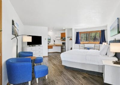 A King Room at Parkside Inn with blue armchairs, the king bed and the kitchenette beyond
