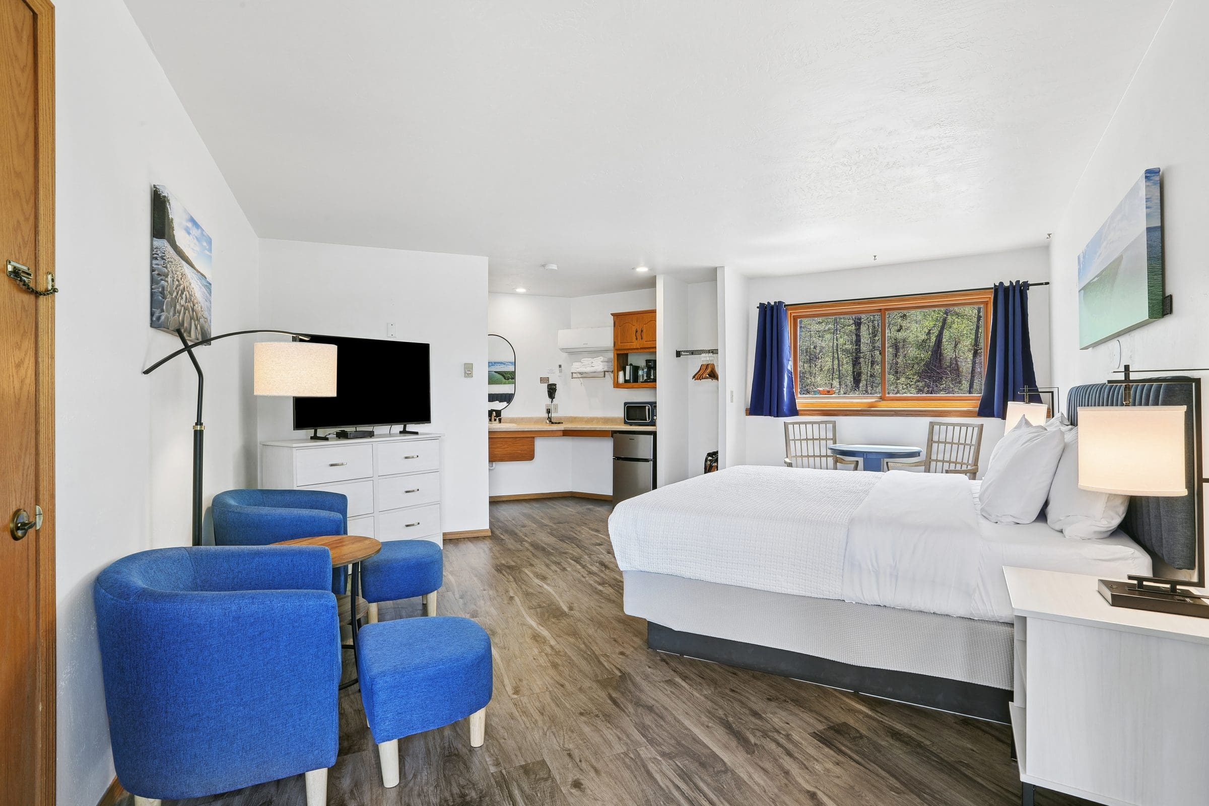 A King Room at Parkside Inn with blue armchairs, the king bed and the kitchenette beyond