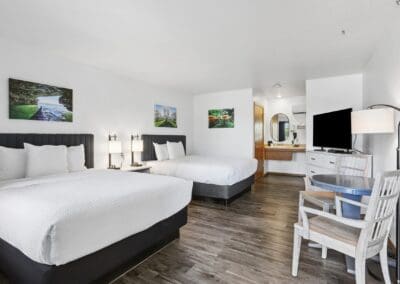 Two queen beds with charcoal headboards and the vanity beyond, in a Two Queen Room at Parkside Inn