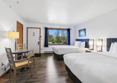 A Two Queen Room seen from the entry, with a table for two by the window and both queen beds