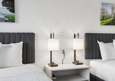 Charcoal upholstered headboards and a shared nightstand between the two queen beds
